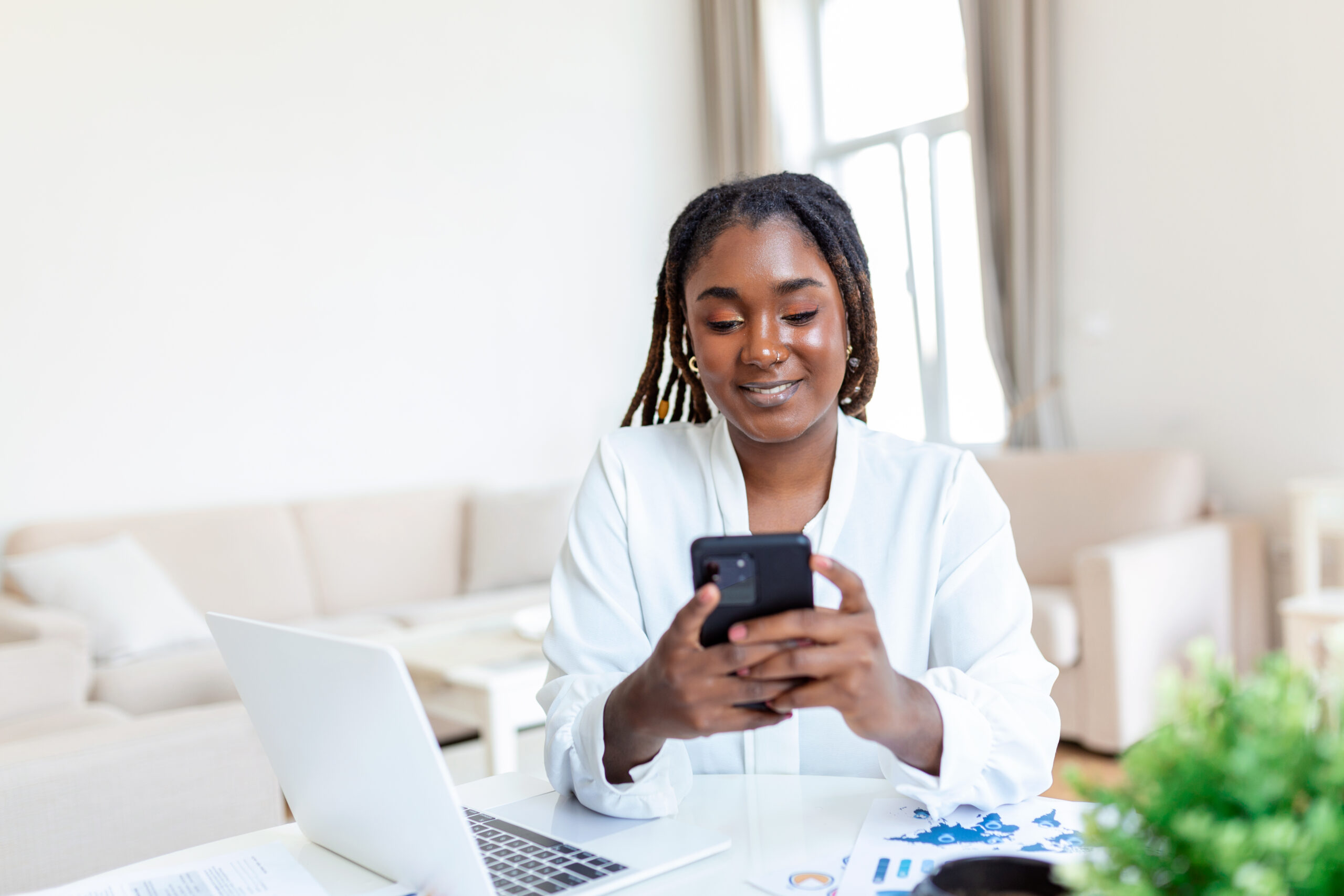 Woman using a smartphone beside a computer in an office